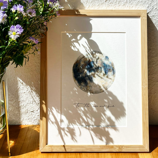 Kunstwerk in einem natürlichen Holzbilderrahmen neben einem Blumenstrauß